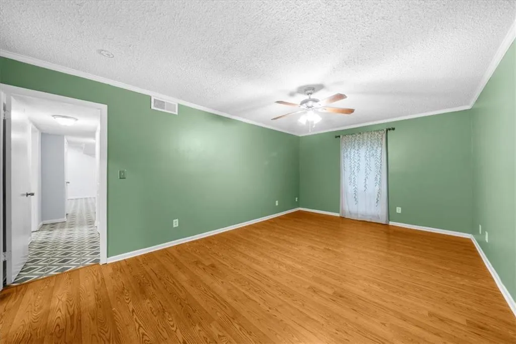 Unfurnished room with ceiling fan, crown molding, wood-type flooring, and a textured ceiling Unfurnished room with ceiling fan, crown molding, wood-type flooring, and a textured ceiling