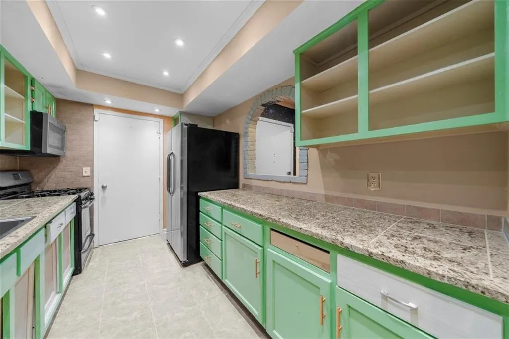 Kitchen with tasteful backsplash, stainless steel appliances, green cabinetry, and ornamental molding Kitchen with tasteful backsplash, stainless steel appliances, green cabinetry, and ornamental molding