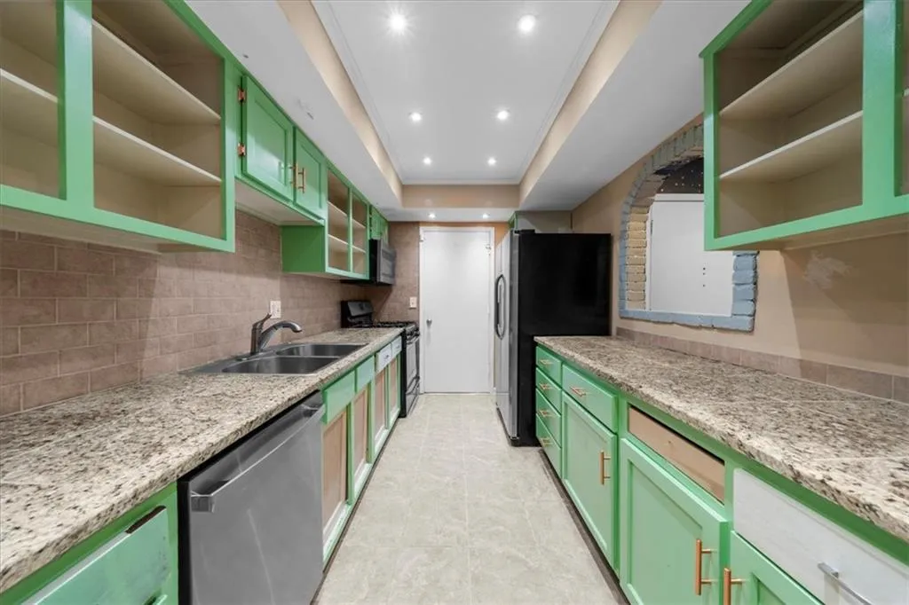 Kitchen with light stone countertops, sink, appliances with stainless steel finishes, and green cabinetry Kitchen with light stone countertops, sink, appliances with stainless steel finishes, and green cabinetry