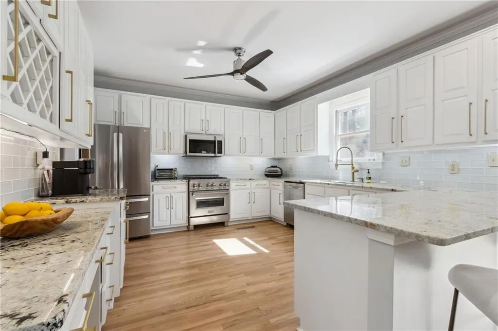 Kitchen with stainless steel appliances, light hardwood / wood-style flooring, tasteful backsplash, ceiling fan, and white cabinetry