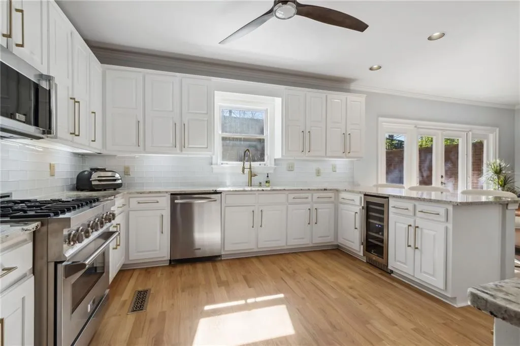Kitchen with light hardwood / wood-style floors, appliances with stainless steel finishes, beverage cooler, and ceiling fan