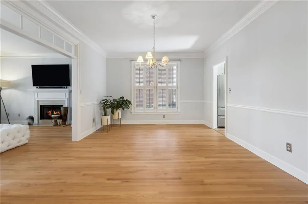 Spare room featuring an inviting chandelier, crown molding, and light wood-type flooring