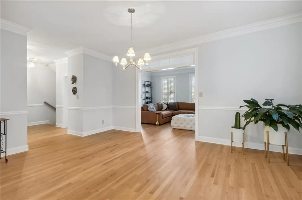Spare room with an inviting chandelier, crown molding, and light wood-type flooring