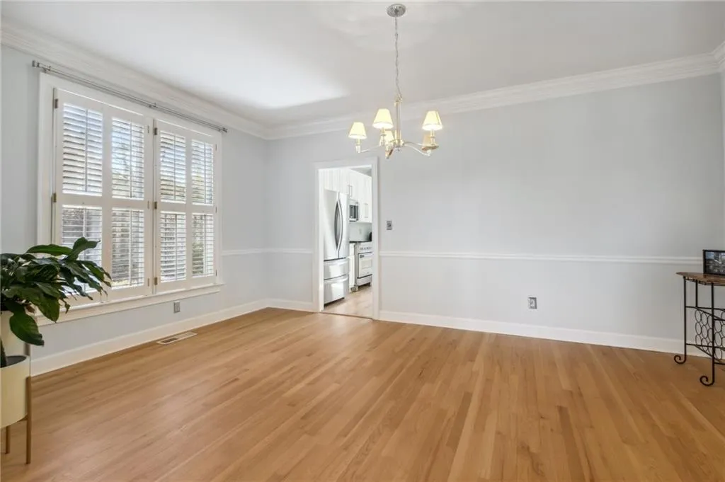 Unfurnished room featuring an inviting chandelier, light wood-type flooring, and crown molding