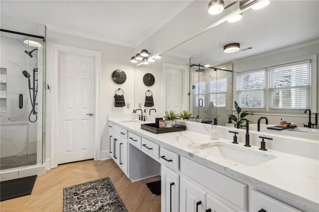 Bathroom with parquet floors, crown molding, a shower with shower door, and dual vanity