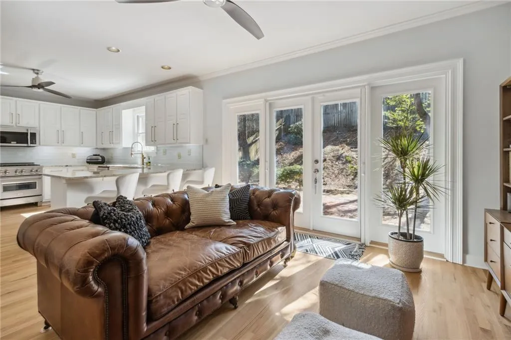 Living room with ceiling fan, ornamental molding, french doors, light hardwood / wood-style flooring, and sink