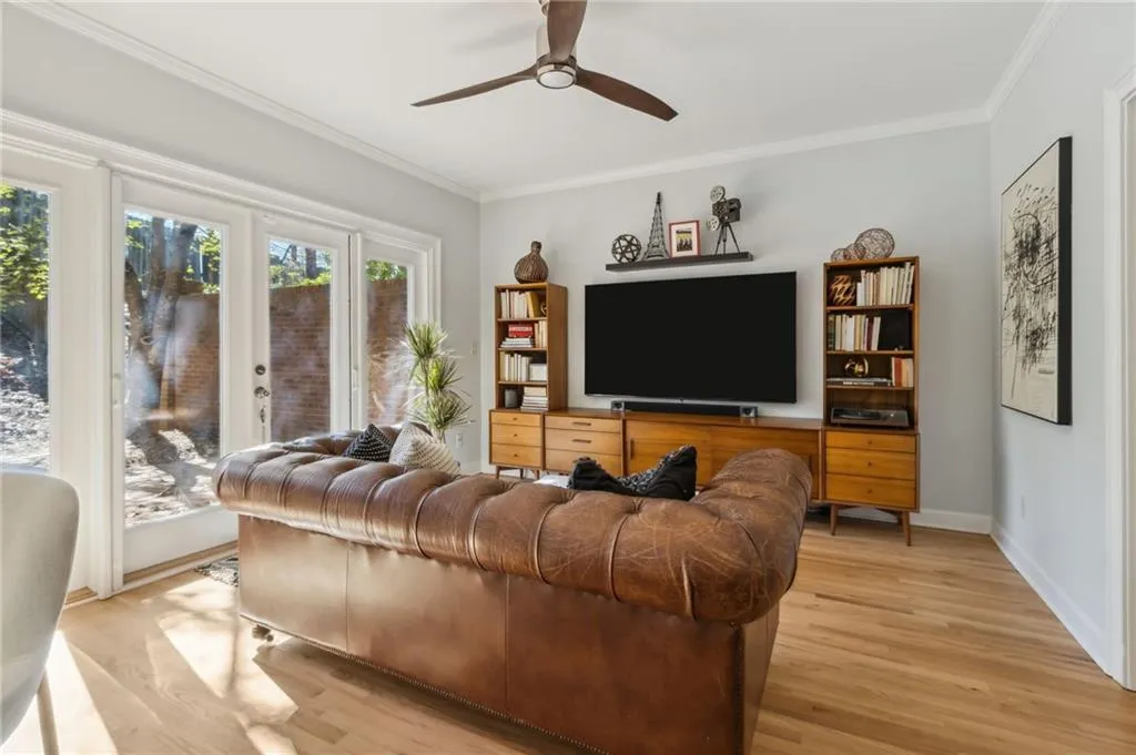 Living room featuring ceiling fan, crown molding, and light hardwood / wood-style floors