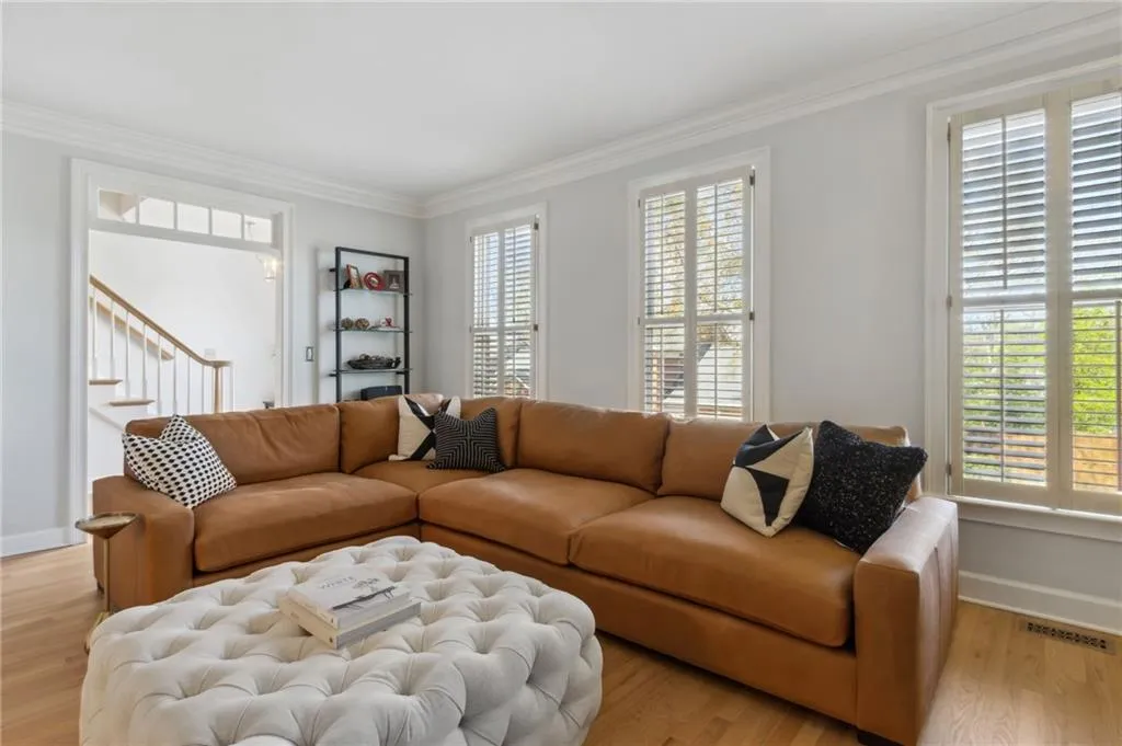 Living room with light hardwood / wood-style floors, crown molding, and a healthy amount of sunlight