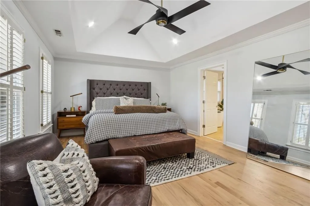 Bedroom featuring a tray ceiling, multiple windows, ceiling fan, and light hardwood / wood-style flooring