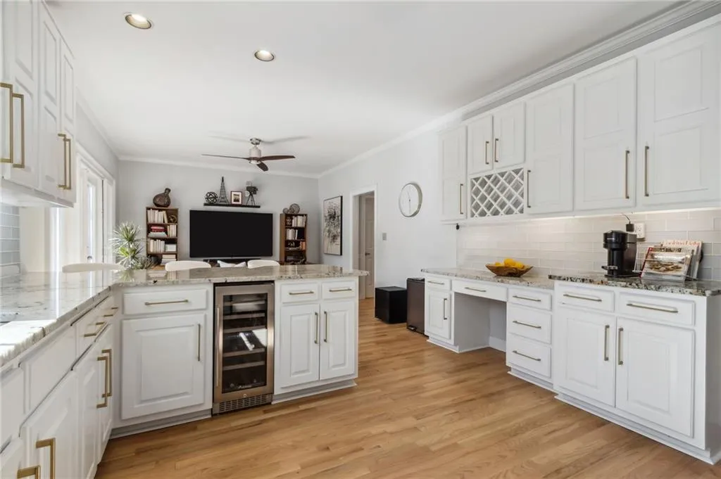 Kitchen featuring backsplash, light wood-type flooring, ceiling fan, white cabinetry, and beverage cooler