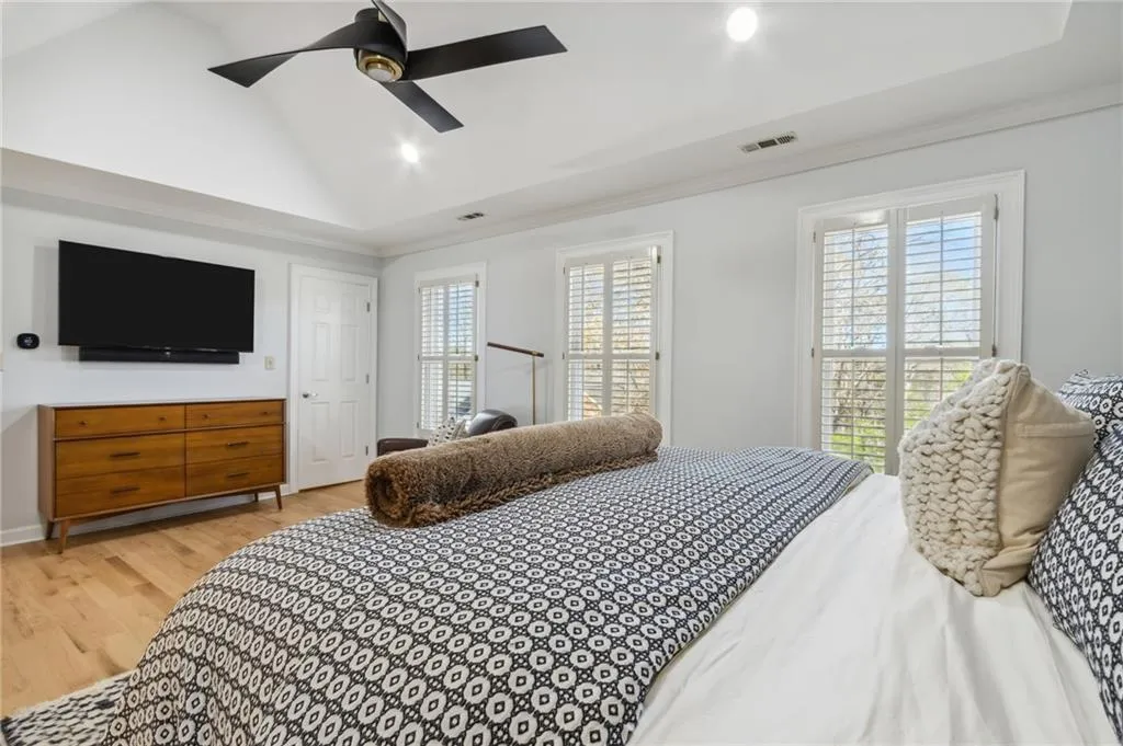 Bedroom featuring multiple windows, a tray ceiling, ceiling fan, and light hardwood / wood-style flooring