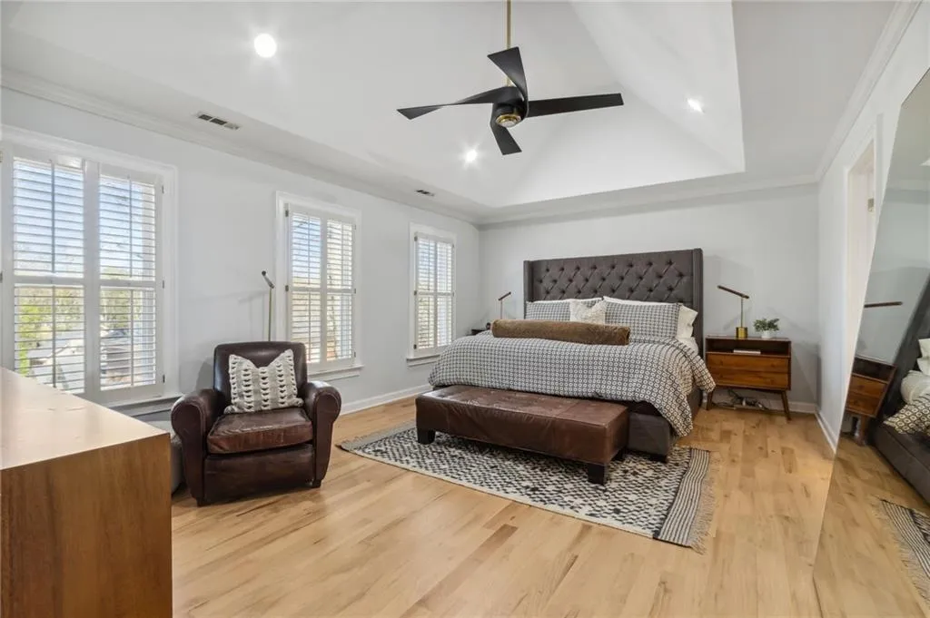 Bedroom featuring light hardwood / wood-style floors, ornamental molding, a raised ceiling, and ceiling fan