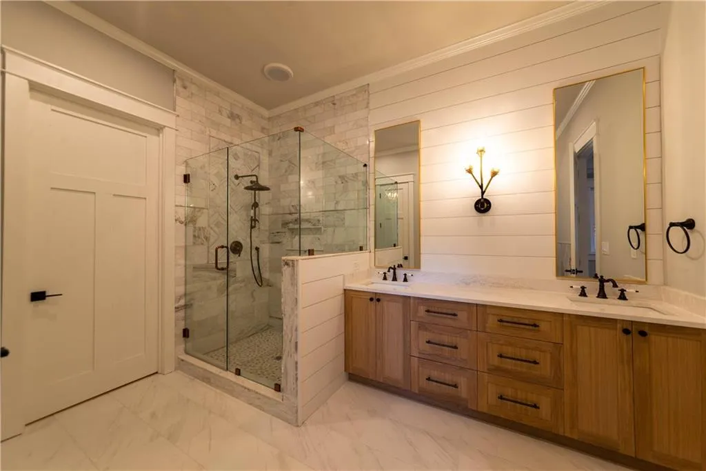 Bathroom featuring wood walls, vanity, a shower with shower door, and ornamental molding