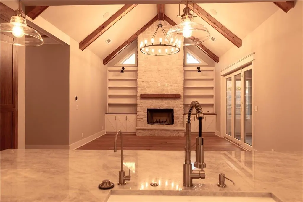 Living room with a notable chandelier, built in shelves, a stone fireplace, and sink