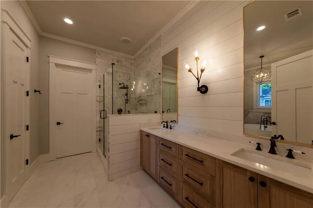 Bathroom with ornamental molding, vanity, an inviting chandelier, and independent shower and bath