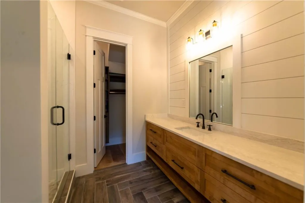 Bathroom featuring ornamental molding, vanity, a shower with door, hardwood / wood-style floors, and wood walls