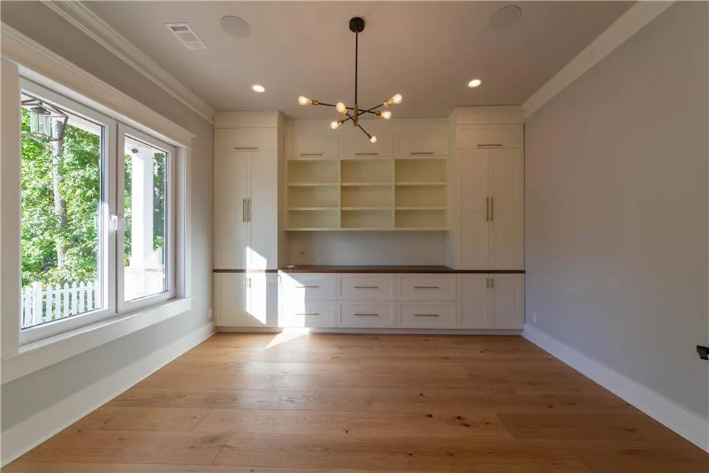 Unfurnished living room with ornamental molding, a notable chandelier, and light wood-type flooring