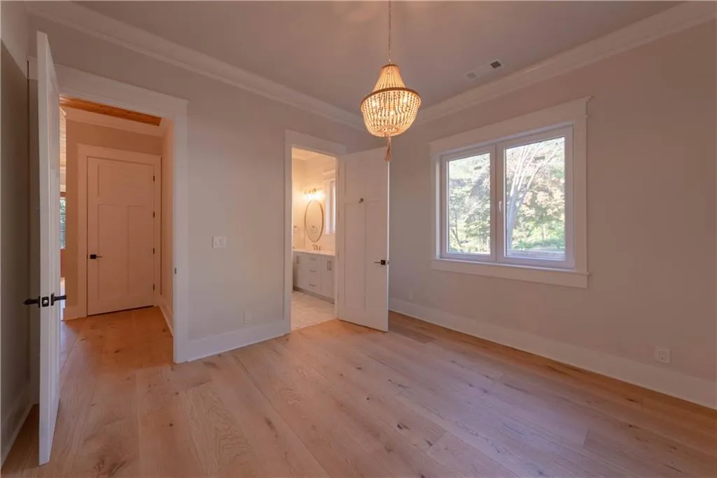 Unfurnished bedroom with a chandelier, ornamental molding, and light hardwood / wood-style flooring
