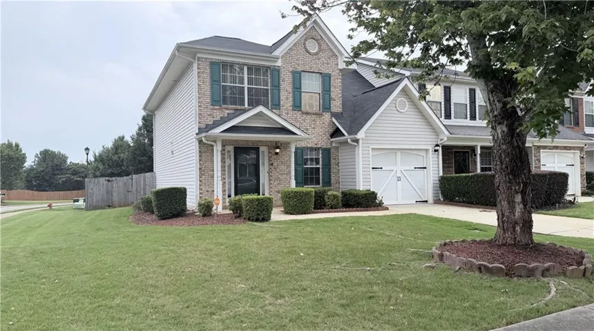 Brick and siding exterior with dark shutters, an attached garage, and a covered front entry