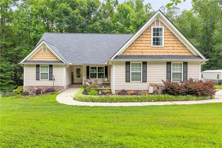 Ranch-style exterior featuring light-colored siding, a dark shingle roof, and decorative shake siding on gables