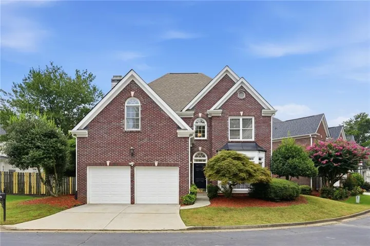 Elegant brick colonial featuring a symmetrical facade with peaked gable roofline and arched entry