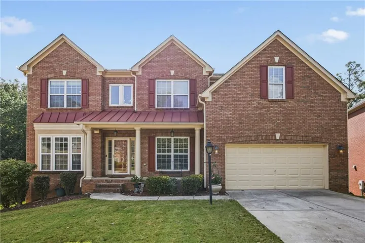 Brick exterior with gabled roof lines, covered front porch, a two-car garage, and red accent shutters