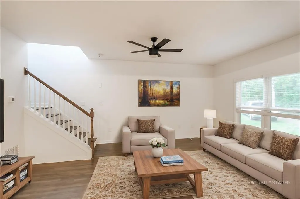 Living room with wood finished floors, stairway, and ceiling fan
