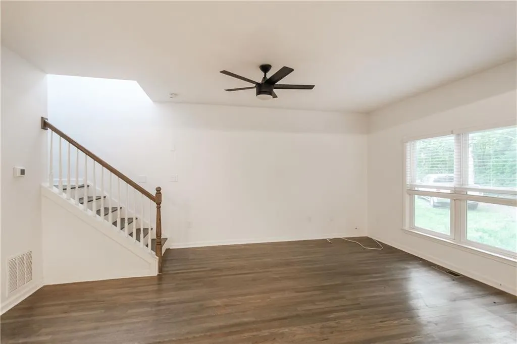 Unfurnished living room with dark wood finished floors, stairs, and ceiling fan