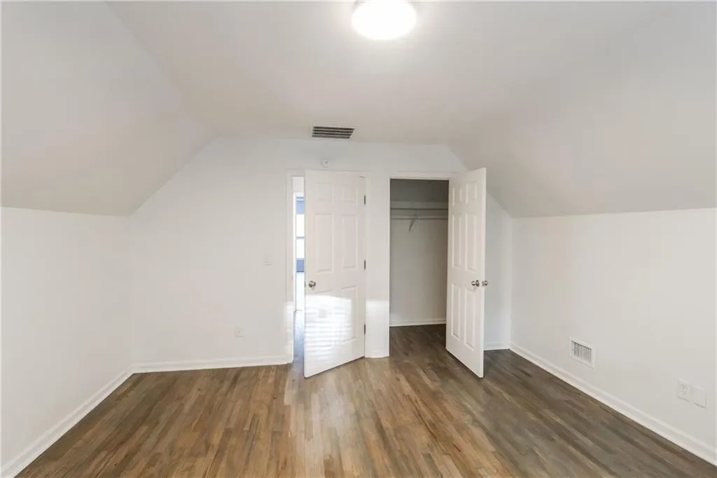 Bonus room with vaulted ceiling and dark wood finished floors