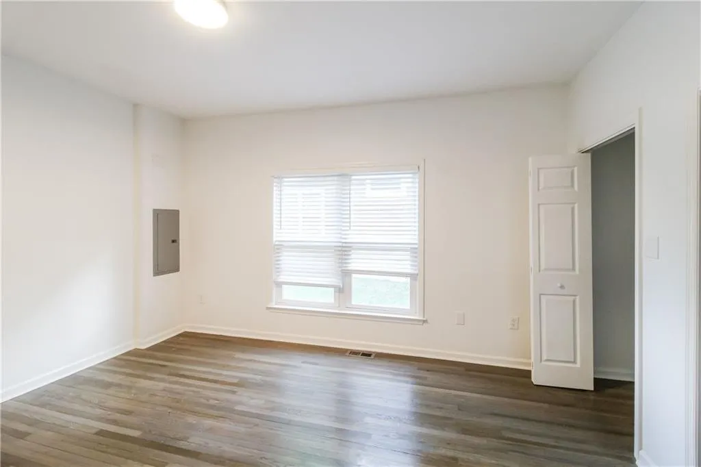 Empty room with dark wood-style floors and electric panel