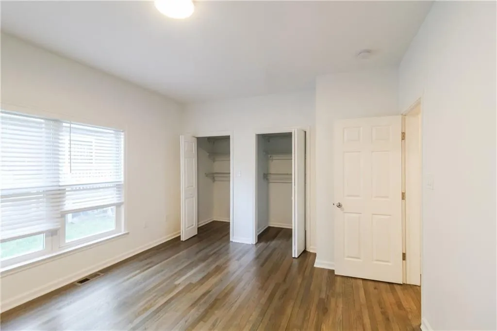 Unfurnished bedroom with multiple closets and wood finished floors