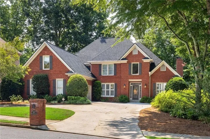Brick exterior with a dark shingle roof, gabled accents, and a paved circular driveway