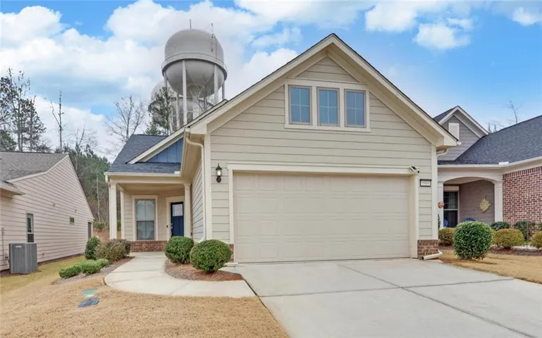 View of front of home with a porch, brick siding, concrete driveway, and roof with shingles