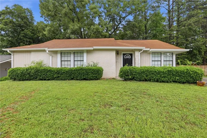 Ranch-style exterior with a brown shingle roof, white gutters, and a dark front door with an arched window insert