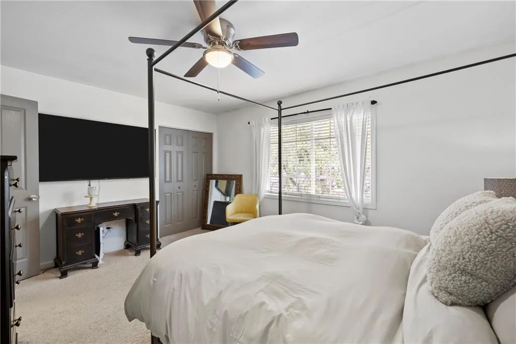 Bedroom featuring light colored carpet, a closet, and a ceiling fan
