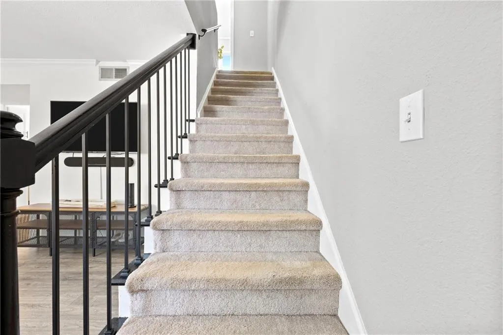 Stairs with wood finished floors and crown molding