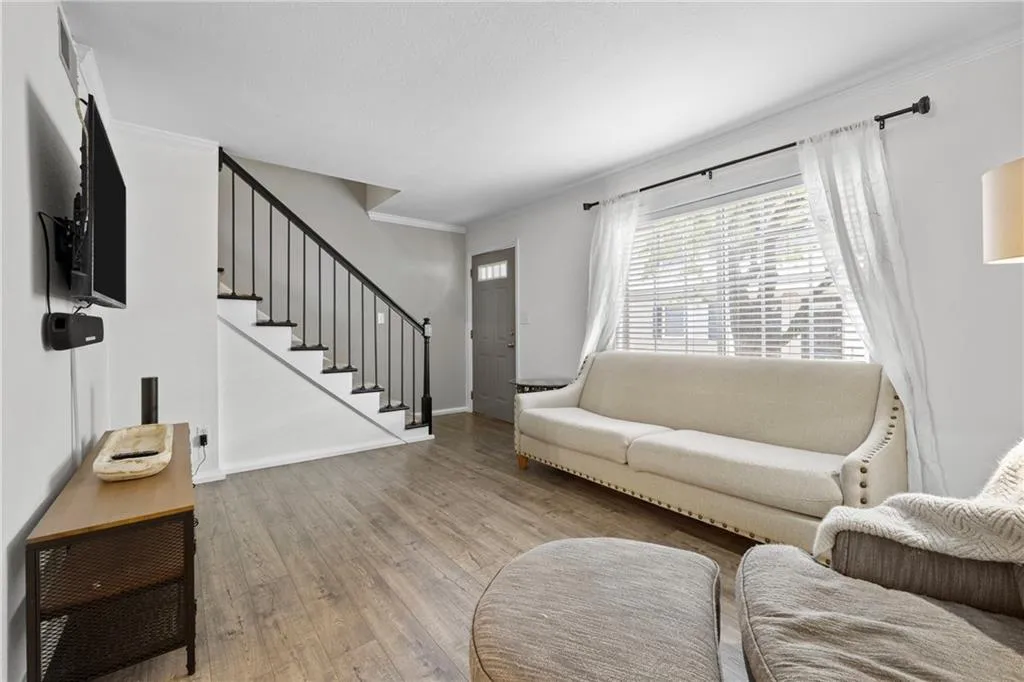 Living area with wood finished floors, ornamental molding, and stairs