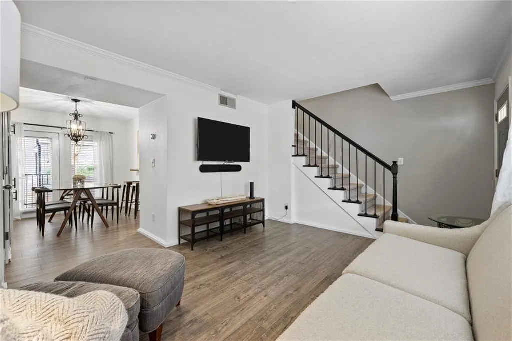 Living area with wood finished floors, stairs, ornamental molding, and a chandelier