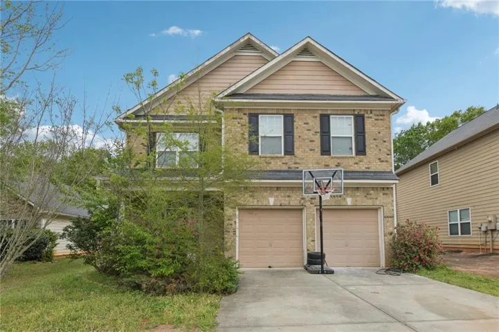 Two-story brick exterior featuring a multi-gabled roofline and a two-car garage