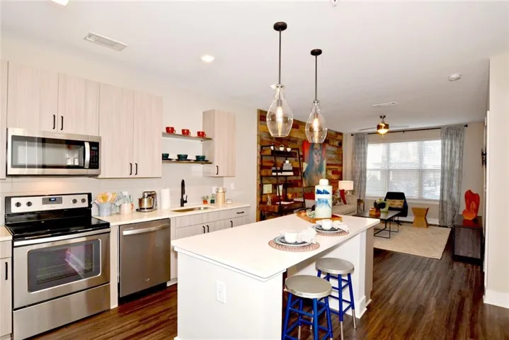 Kitchen with stainless steel appliances, sink, hanging light fixtures, dark hardwood / wood-style floors, and ceiling fan