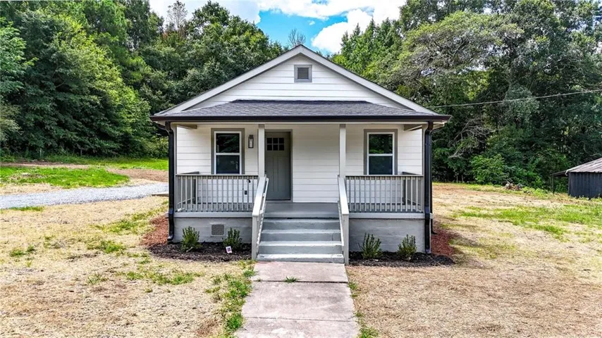 Inviting exterior with white siding, dark gray trim, covered front porch, gray handrails, and a solid gray front door