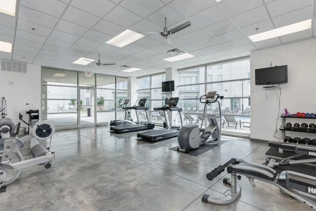 Exercise room with expansive windows, a ceiling fan, and a paneled ceiling