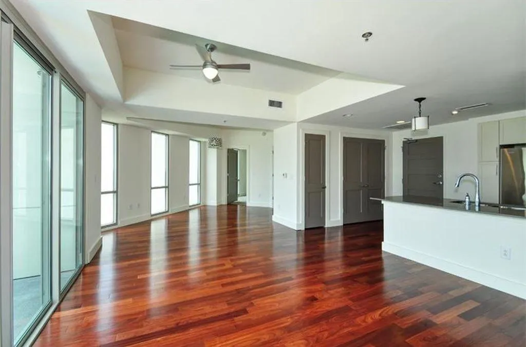 Unfurnished living room with a tray ceiling, dark wood-style flooring, and ceiling fan