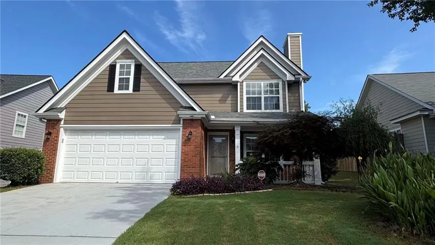 Two-story residence featuring a two-car garage, brick accents, and a gabled roofline