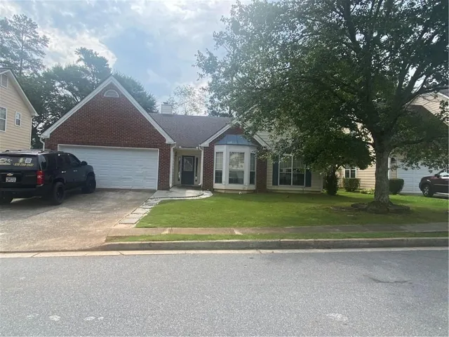 Single-story residence featuring a brick facade with a prominent white garage door and an arched window detail in the front gable