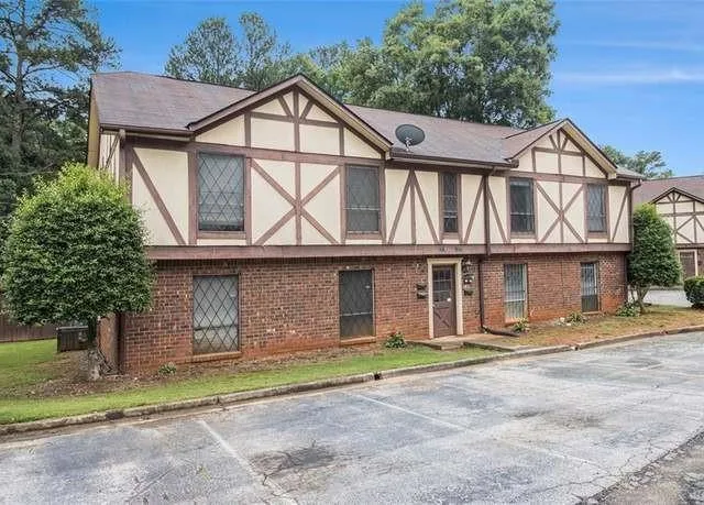 Tudor house featuring stucco siding, uncovered parking, and brick siding