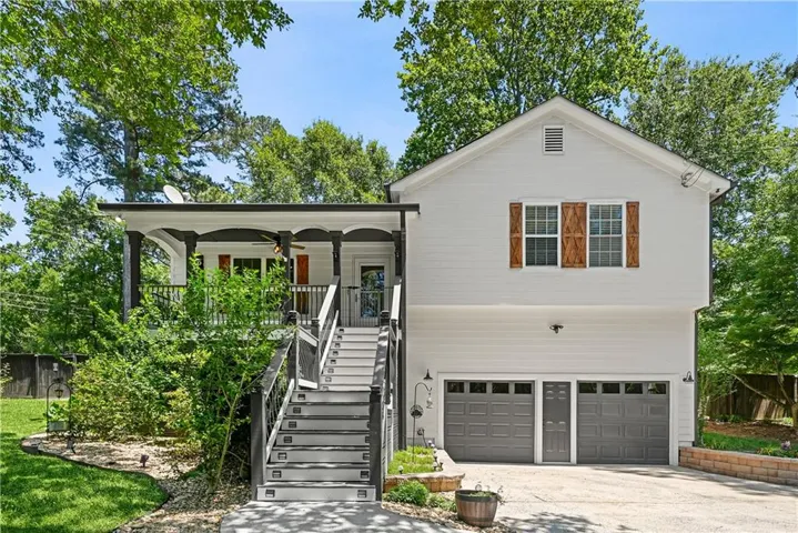 Two-story residence featuring white siding, a covered upper-level porch, and a two-car garage