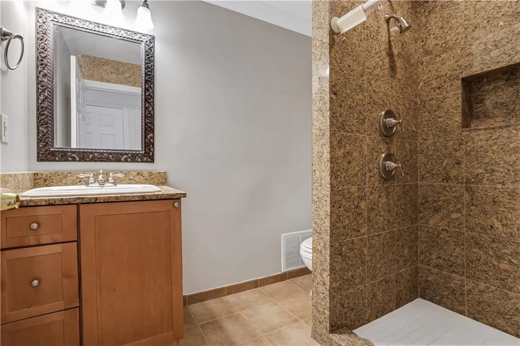 Full bath featuring a stall shower, vanity, and light tile patterned floors