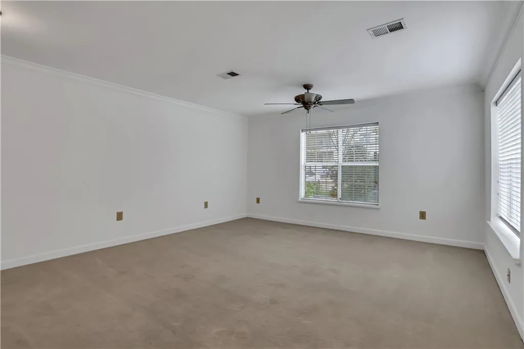 Empty room with ornamental molding, light carpet, healthy amount of natural light, and a ceiling fan