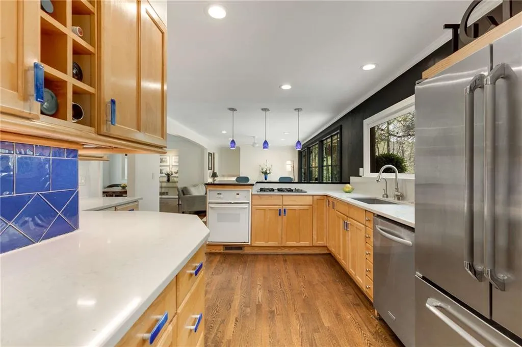 Kitchen with a sink, light countertops, a peninsula, stainless steel appliances, and dark wood-type flooring